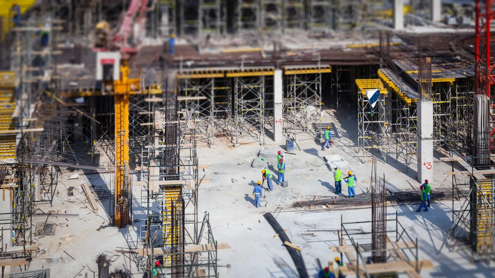 Großbaustelle von oben mit Arbeitern in Warnwesten zwischen Gerüsten