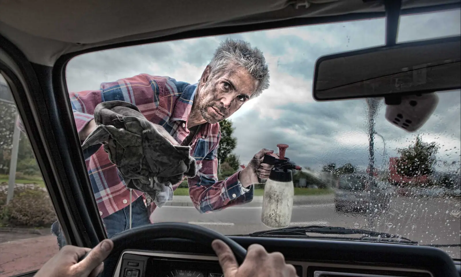 Mann reinigt eine Windschutzscheibe, fotografiert aus dem Inneren des Fahrzeugs