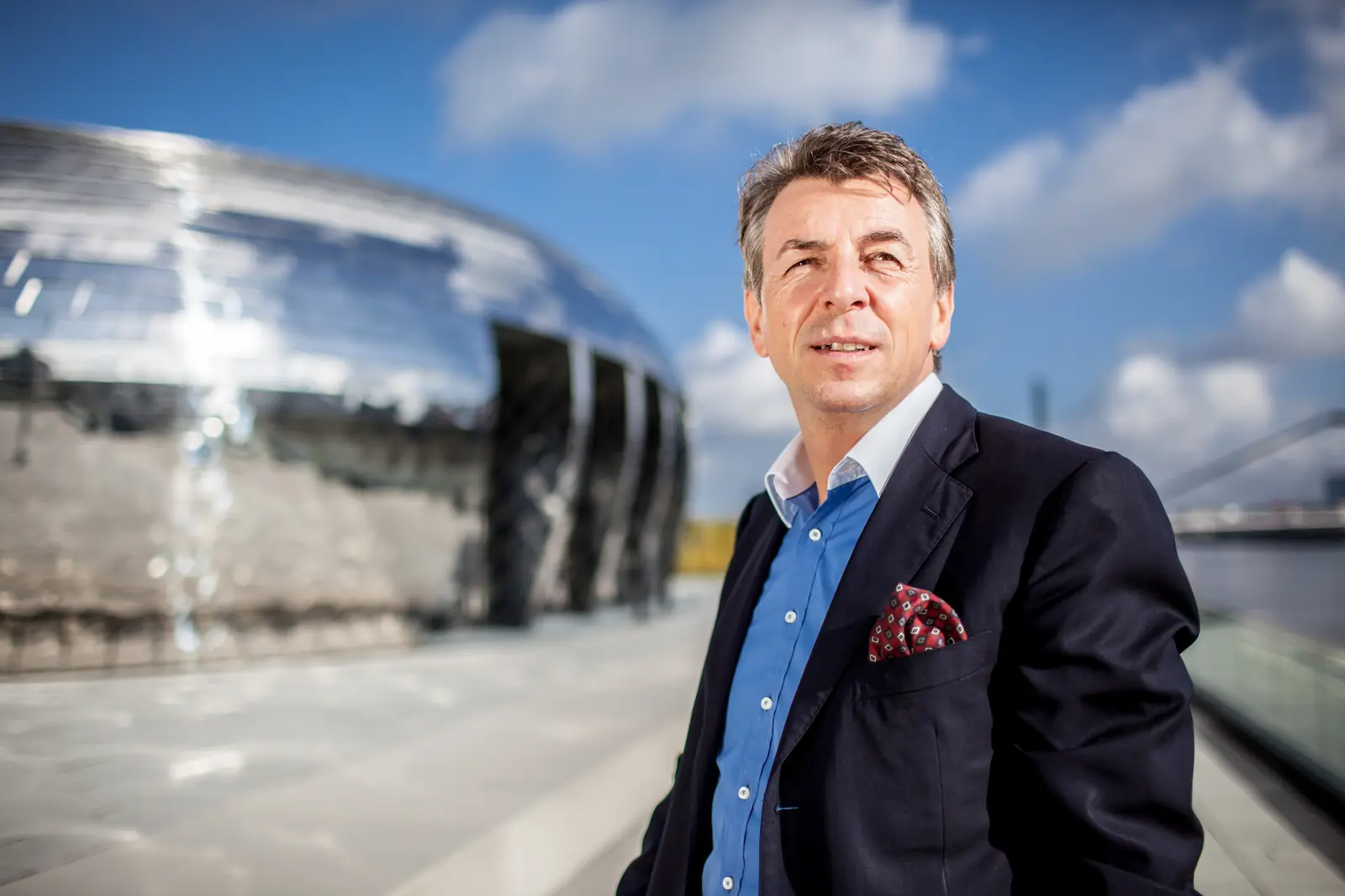 Motivationstrainer Dirk Schmidt im Anzug vor einem verspiegelten Kuppelbau