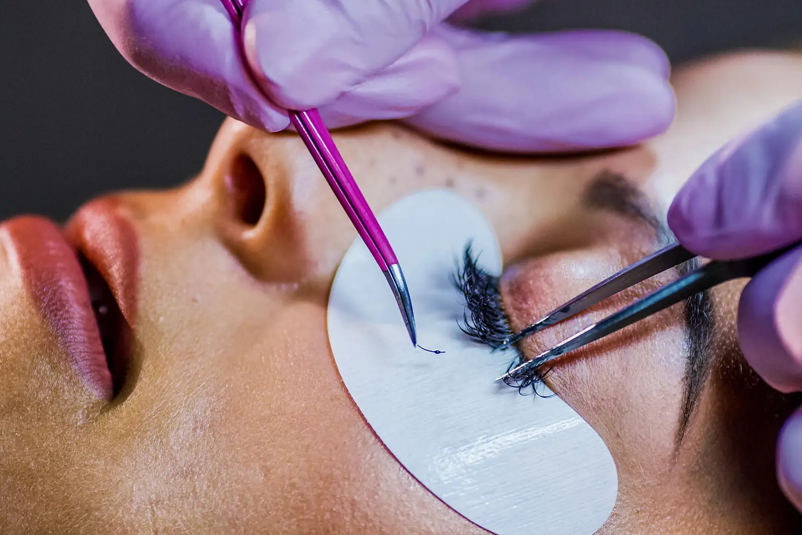 Nahaufnahme einer Wimpernverlängerung mit Pinzette